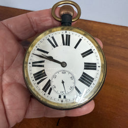 Vintage pocket watch held in a hand with a wooden surface in the background