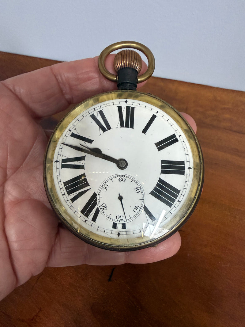 Vintage pocket watch held in a hand with a wooden surface in the background