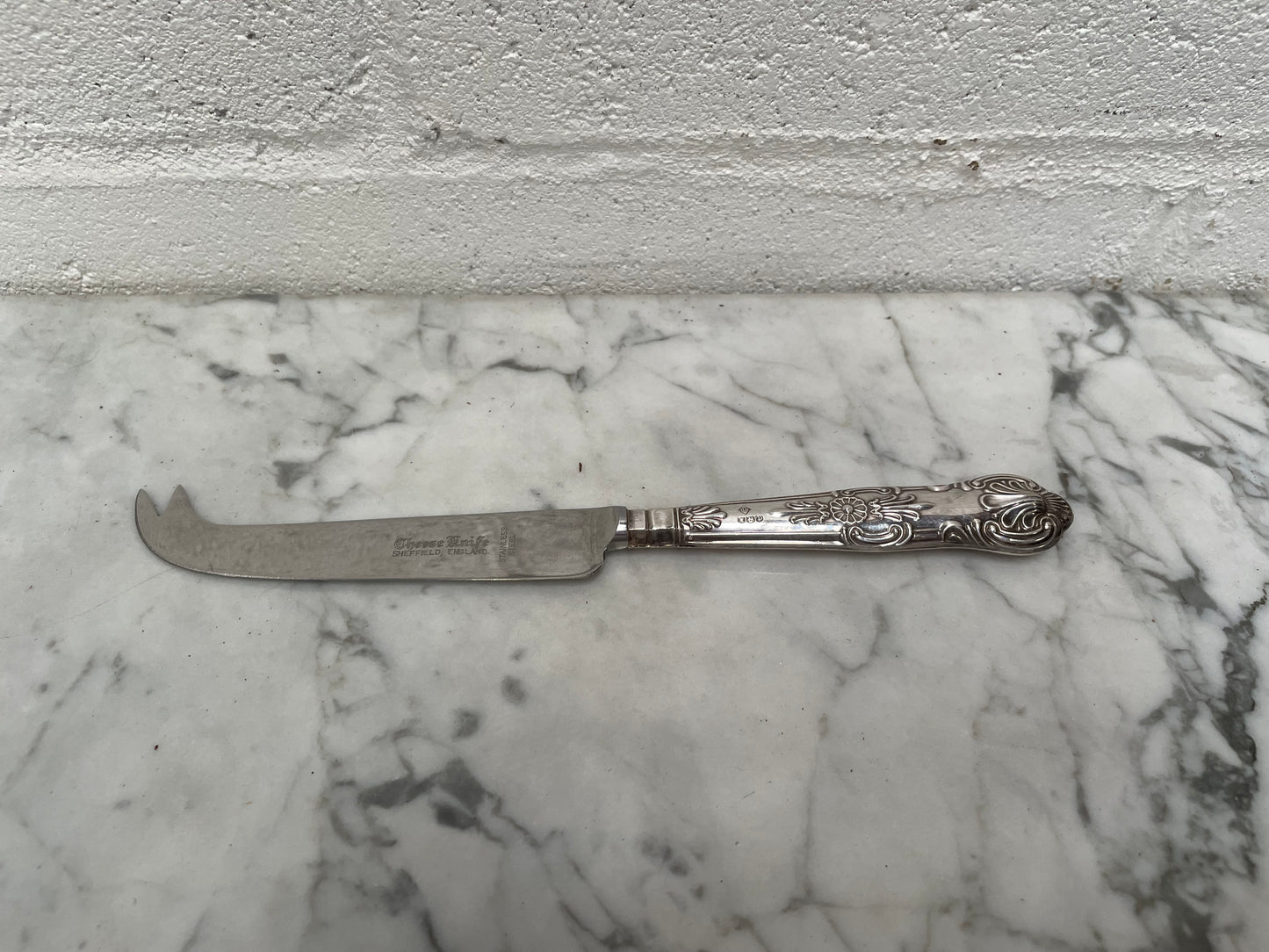 Decorative Sheffield sterling silver cheese knife. The handle has sterling silver hallmarks and the blade is stainless steel. Made in England and is in good original condition. 
