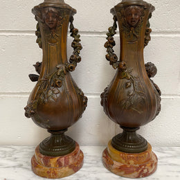 Pair of French Bronzed Metal Cherub Urns on a Marble Base