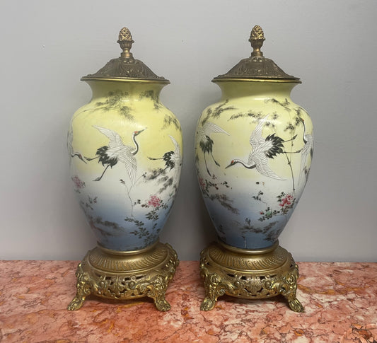 Attractive pair of Japanese urns. Hand painted depicting cranes and with brass mounts. In good original condition. Please see photos as they form part of the description.