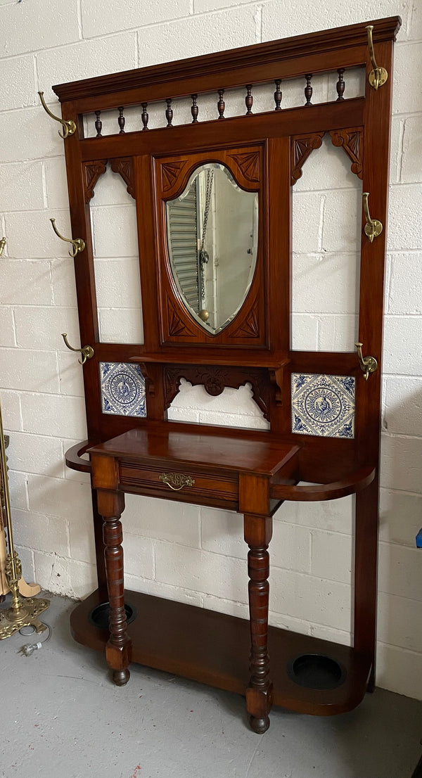 Lovely Edwardian single drawer shield mirror mahogany hall stand. It has 6 hooks for hanging and two pretty decorative blue and white tiles. In good original condition