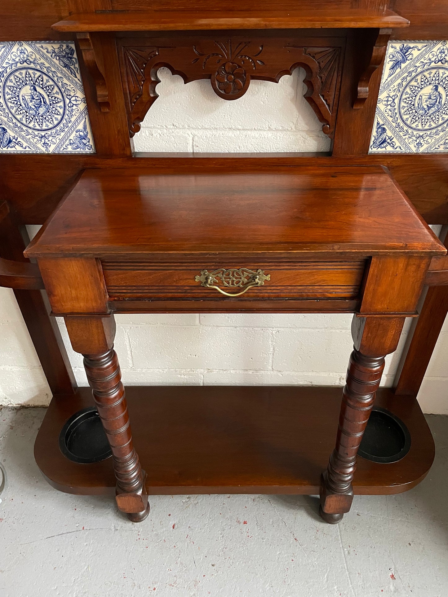 Lovely Edwardian single drawer shield mirror mahogany hall stand. It has 6 hooks for hanging and two pretty decorative blue and white tiles. In good original condition