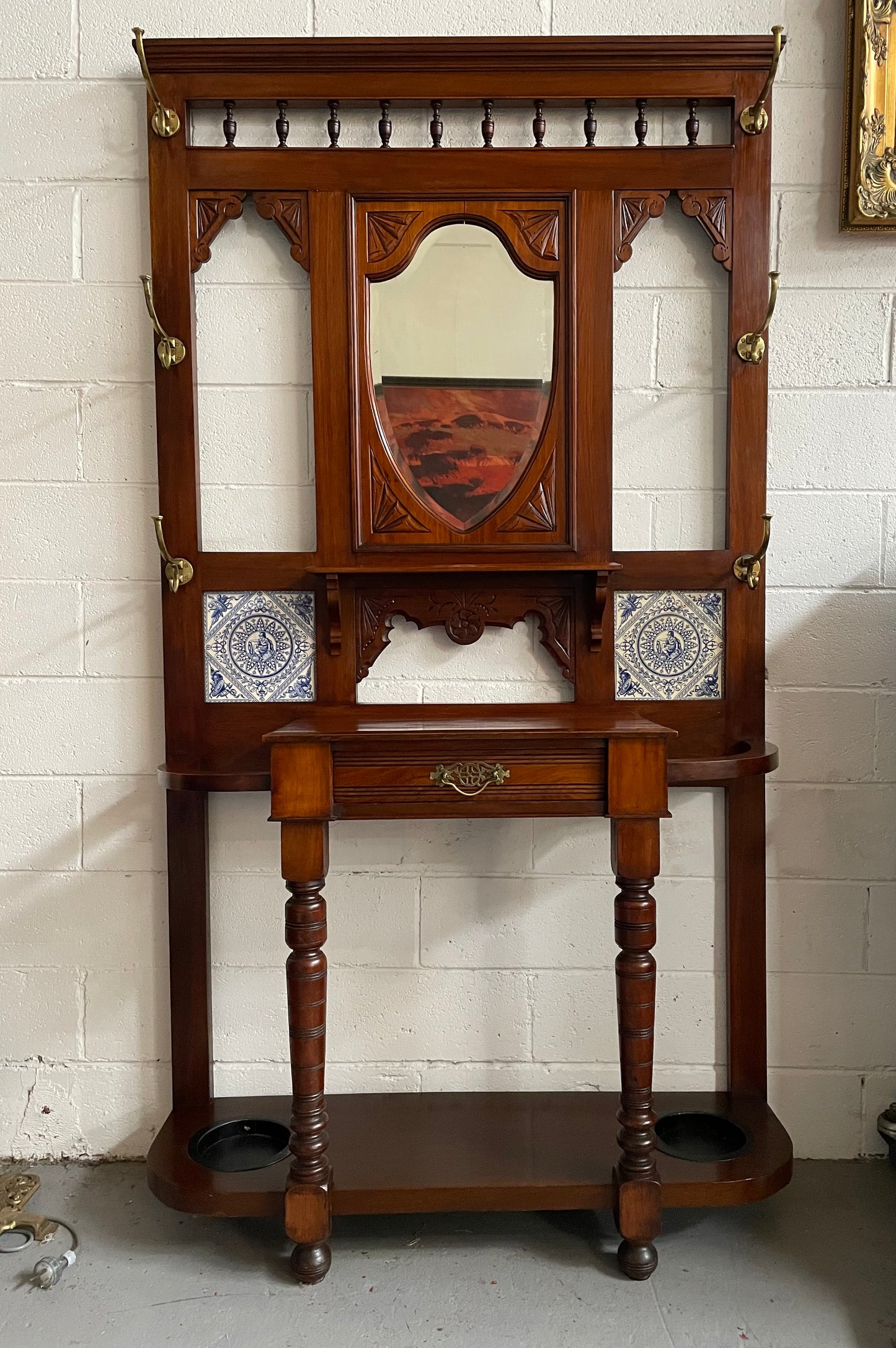Lovely Edwardian single drawer shield mirror mahogany hall stand. It has 6 hooks for hanging and two pretty decorative blue and white tiles. In good original condition