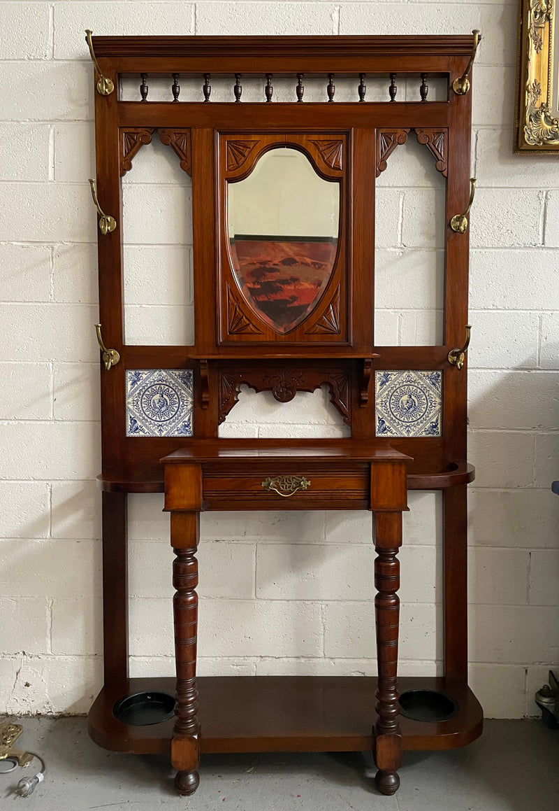 Lovely Edwardian single drawer shield mirror mahogany hall stand. It has 6 hooks for hanging and two pretty decorative blue and white tiles. In good original condition