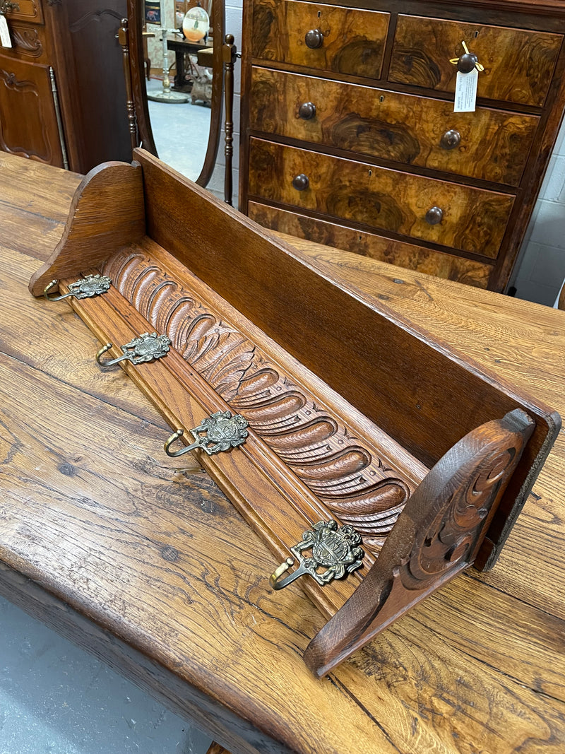 French oak wall coat rack with four decorative hooks and shelf. It has been sourced from France and is in good original condition. 