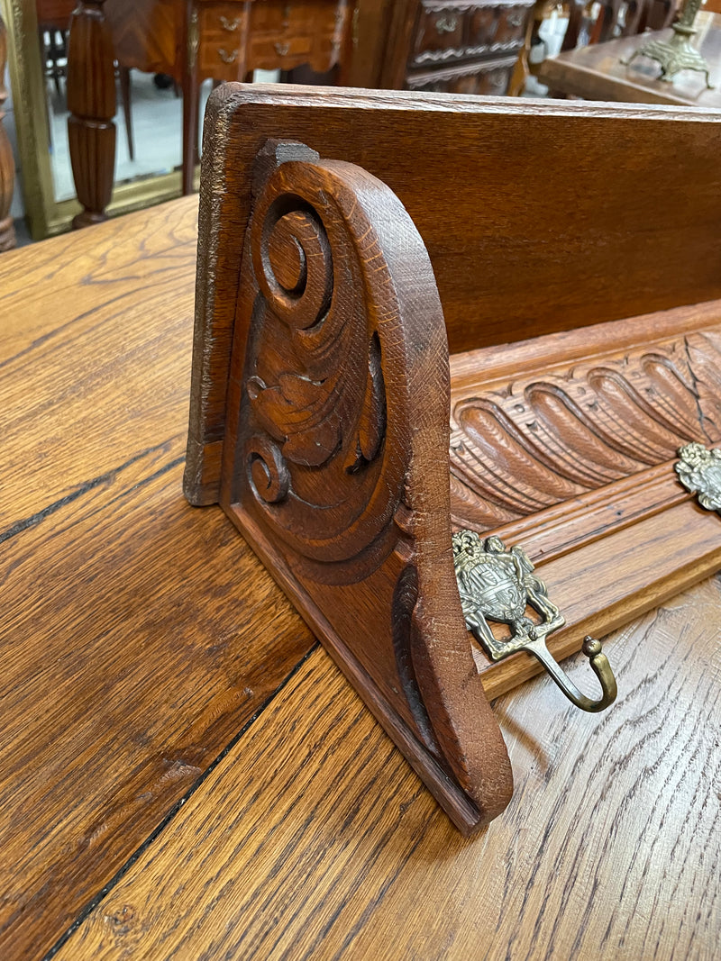 French oak wall coat rack with four decorative hooks and shelf. It has been sourced from France and is in good original condition. 