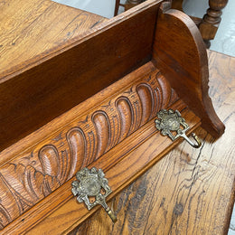 French oak wall coat rack with four decorative hooks and shelf. It has been sourced from France and is in good original condition. 