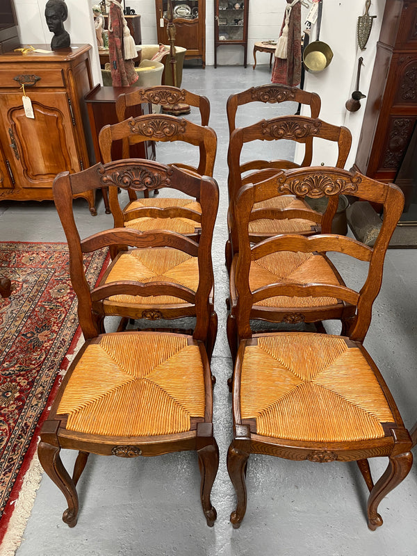 Lovely set of six French rush seat dining chairs. They feature decorative carved detailing particularly to the top of the chair. They are in good original detailed condition and have been sourced from France. 