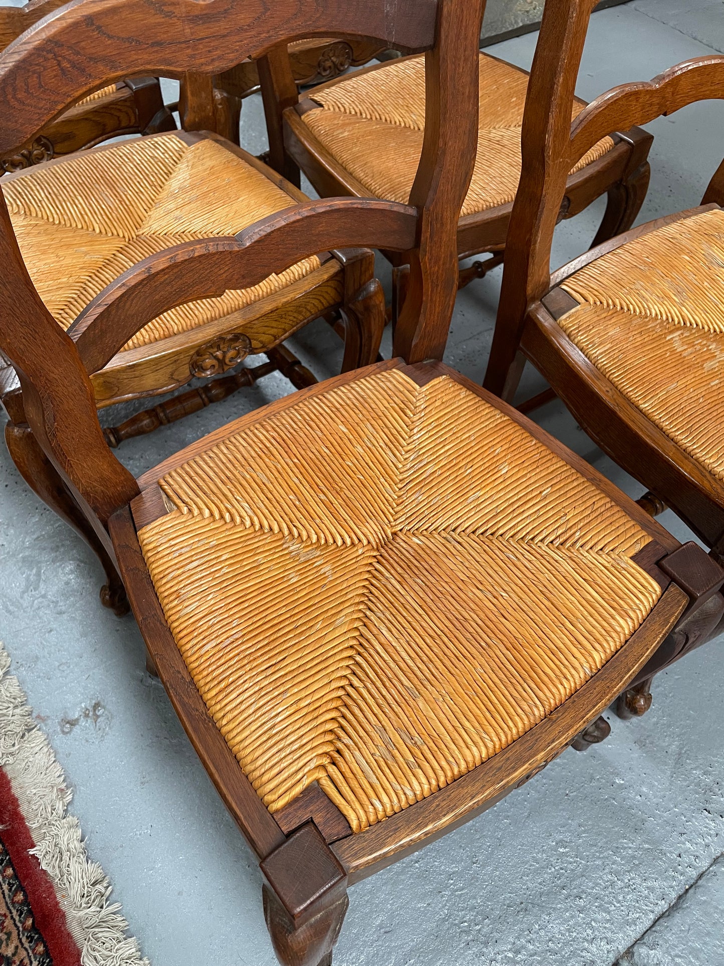 Lovely set of six French rush seat dining chairs. They feature decorative carved detailing particularly to the top of the chair. They are in good original detailed condition and have been sourced from France. 