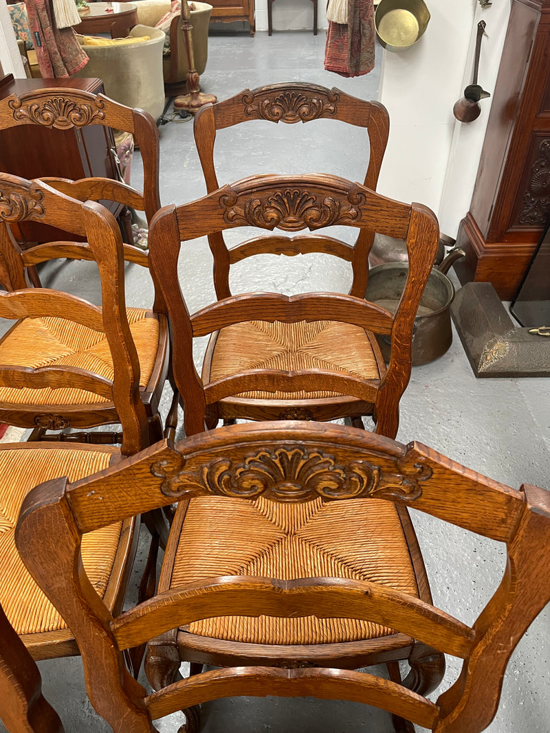 Lovely set of six French rush seat dining chairs. They feature decorative carved detailing particularly to the top of the chair. They are in good original detailed condition and have been sourced from France. 