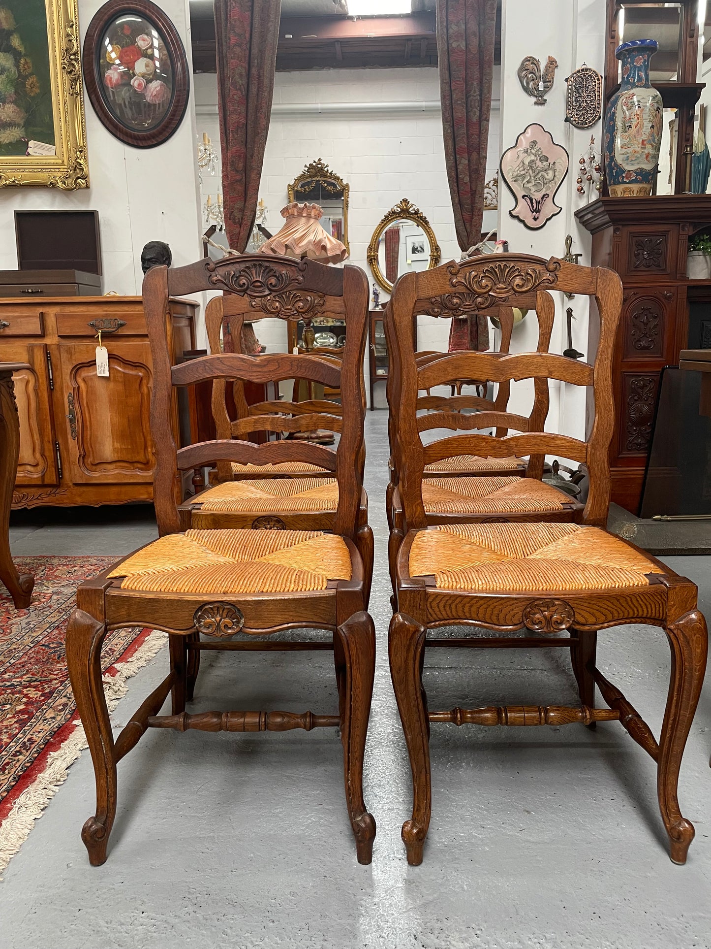 Lovely set of six French rush seat dining chairs. They feature decorative carved detailing particularly to the top of the chair. They are in good original detailed condition and have been sourced from France. 