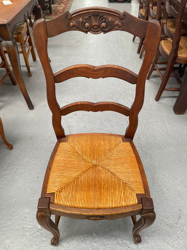 Lovely set of six French rush seat dining chairs. They feature decorative carved detailing particularly to the top of the chair. They are in good original detailed condition and have been sourced from France. 