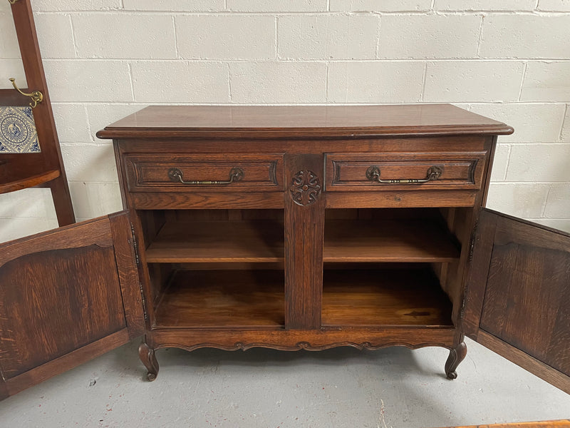 Charming French Oak provincial two door buffet. It has two drawers and a cupboard with two doors and one shelf. It is in good original condition and has been sourced directly from France.