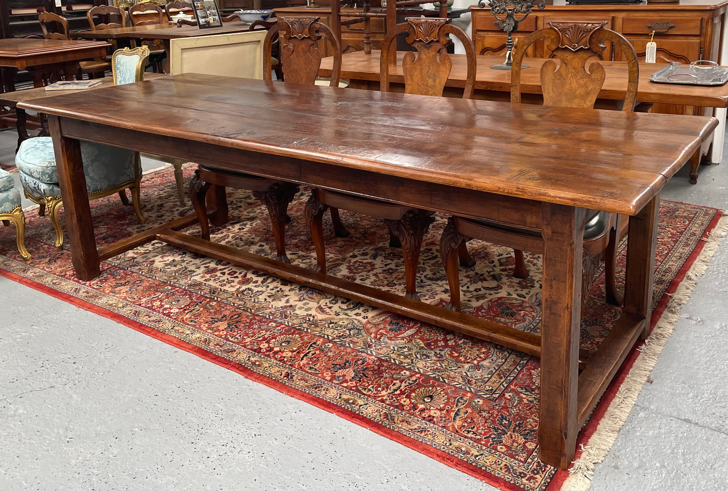 Rustic stretcher base dining table. The top consists of four heavy planks of French Oak timber. The surface is rustic and a little uneven and would require the use of place mats to even out. Please see photos as they form part of the description.