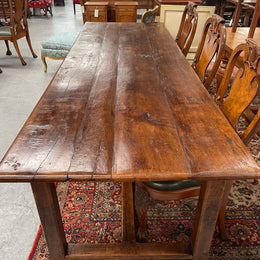 Rustic stretcher base dining table. The top consists of four heavy planks of French Oak timber. The surface is rustic and a little uneven and would require the use of place mats to even out. Please see photos as they form part of the description.