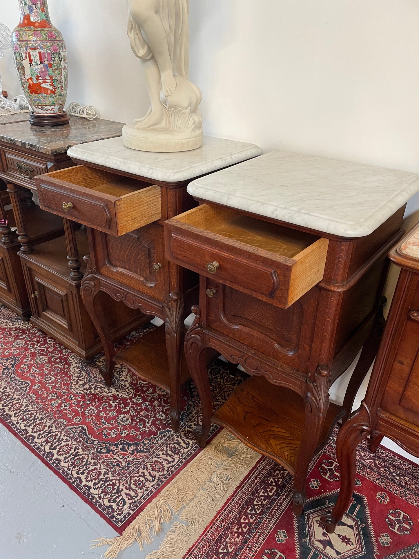 Beautifully carved pair of French Oak bedside cabinets with marble tops and inserts . They consist of one drawer and one cupboard. Featuring classic Louis 15th style curved legs and in good original detailed condition. They have been imported directly from France. 