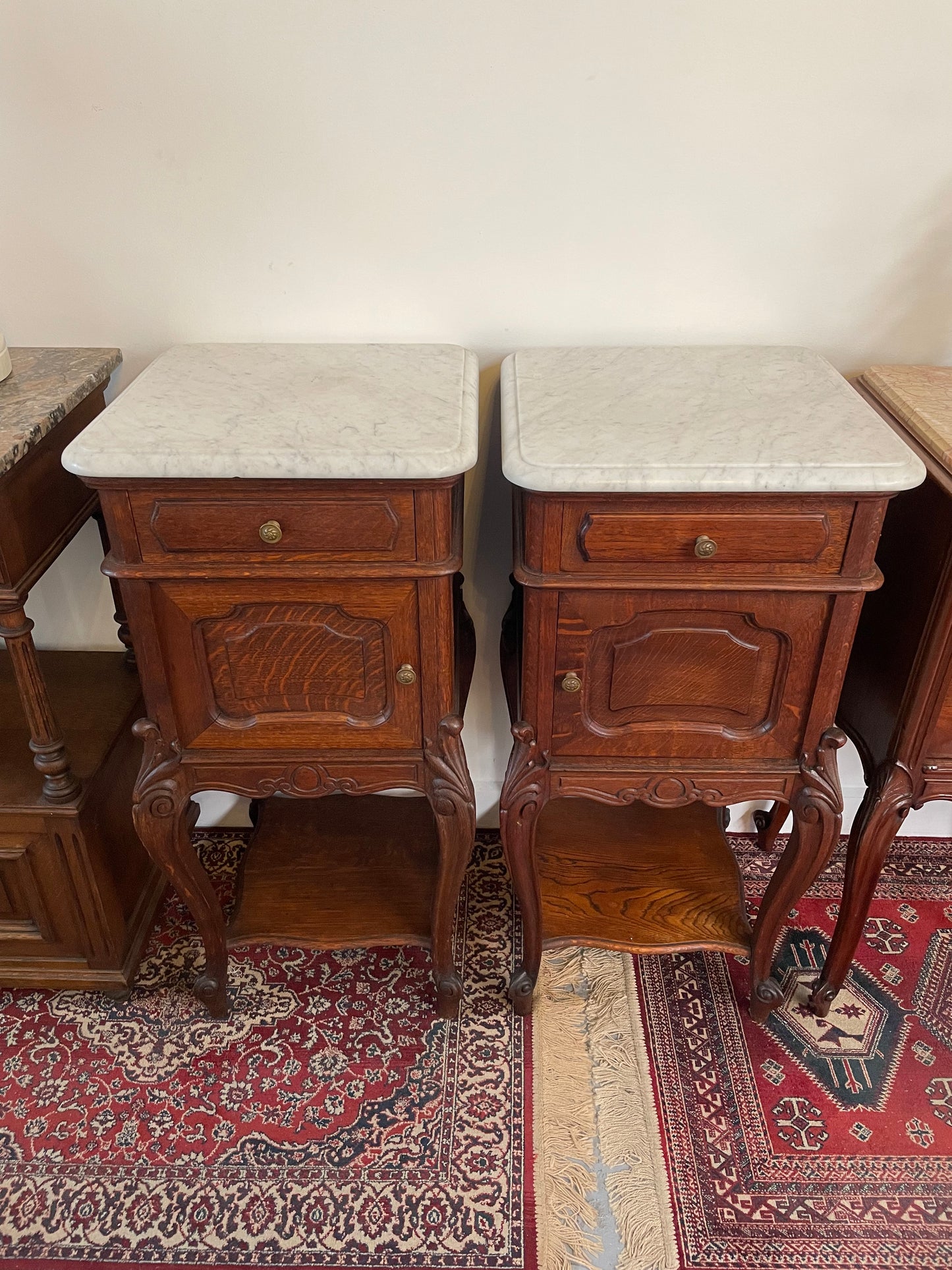 Beautifully carved pair of French Oak bedside cabinets with marble tops and inserts . They consist of one drawer and one cupboard. Featuring classic Louis 15th style curved legs and in good original detailed condition. They have been imported directly from France. 