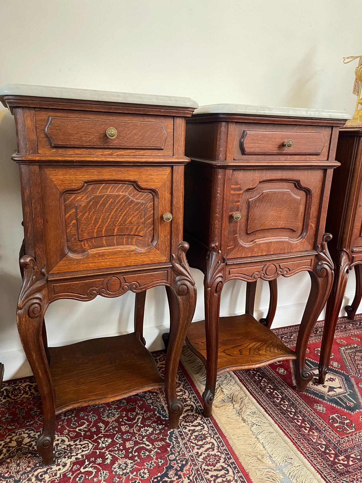 Beautifully carved pair of French Oak bedside cabinets with marble tops and inserts . They consist of one drawer and one cupboard. Featuring classic Louis 15th style curved legs and in good original detailed condition. They have been imported directly from France. 