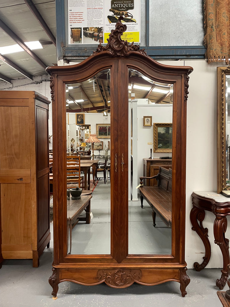 French Walnut Louis XV style two mirrored door armoire. It has four full adjustable shelves and two drawers at the bottom with one that locks. It has been sourced directly from France and is in good original detailed condition.