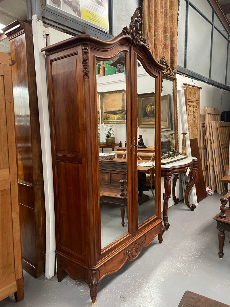 French Walnut Louis XV style two mirrored door armoire. It has four full adjustable shelves and two drawers at the bottom with one that locks. It has been sourced directly from France and is in good original detailed condition.