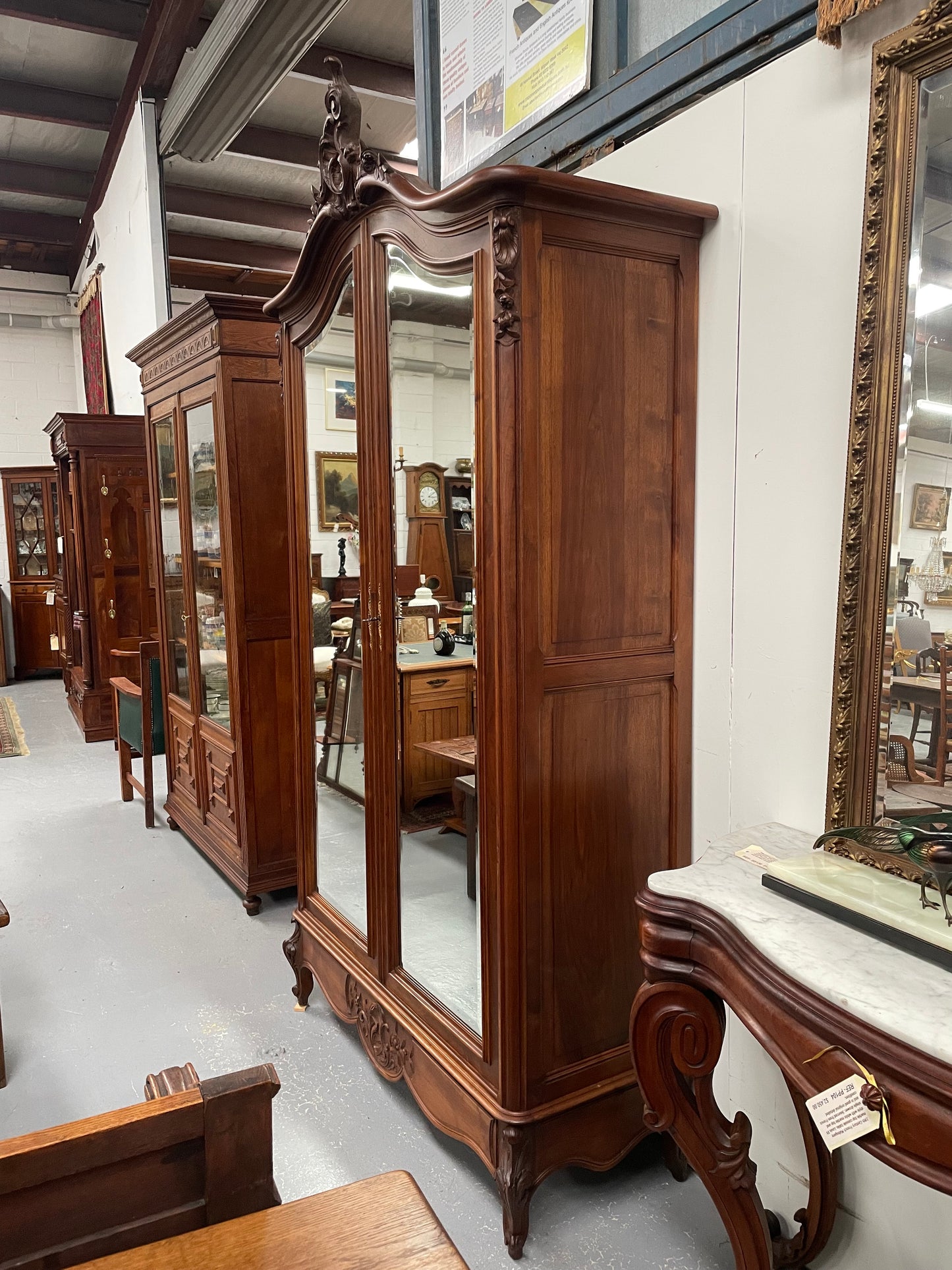 French Walnut Louis XV style two mirrored door armoire. It has four full adjustable shelves and two drawers at the bottom with one that locks. It has been sourced directly from France and is in good original detailed condition.