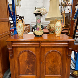 Cedar cupboard / side cabinet with two drawers above a pair of figured paneled doors, decorated with two corbels and on a plinth base. In good original condition and sourced locally.