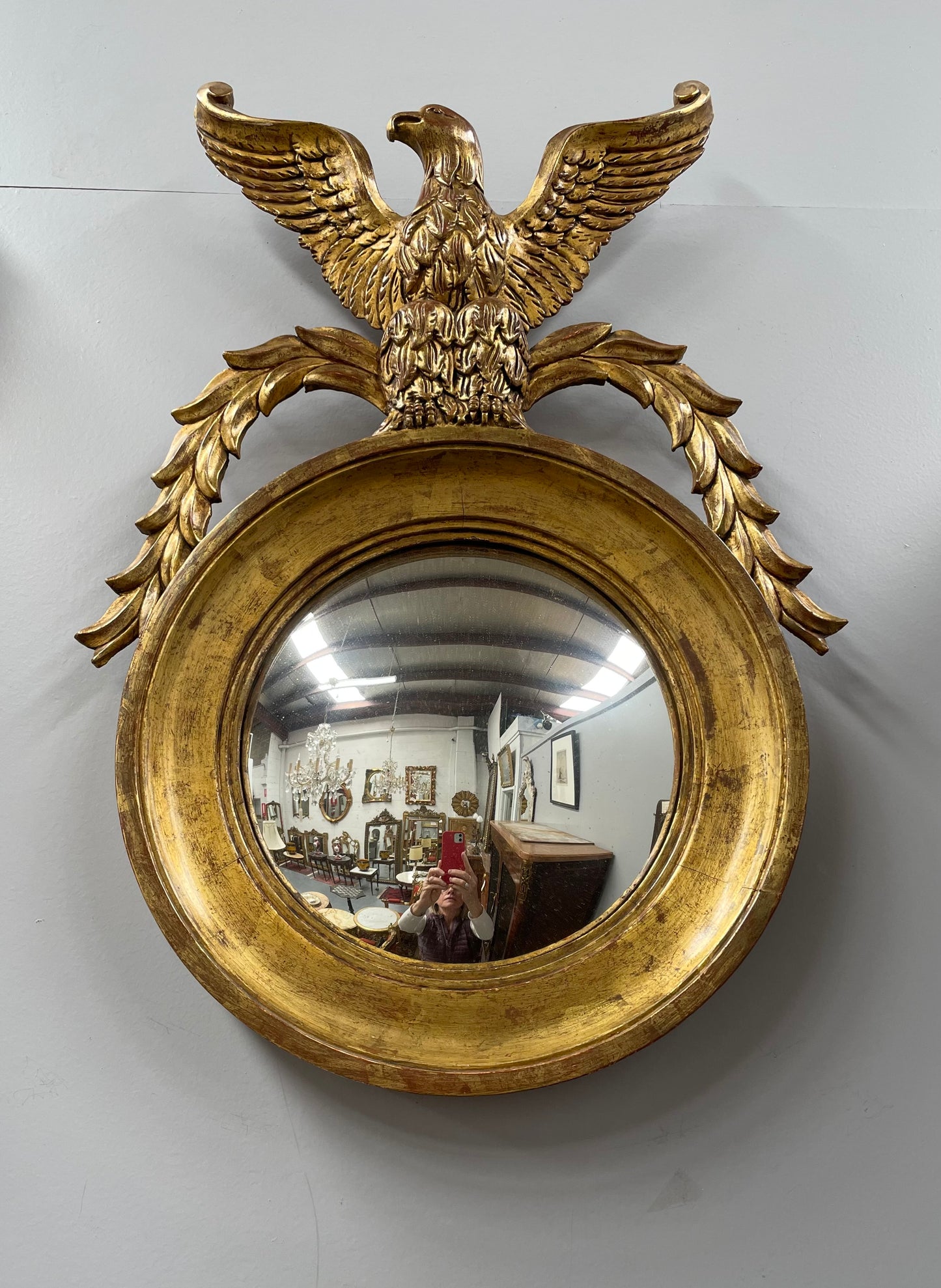 A stunning round carved wooden eagle convex hanging mirror. The eagle theme adds a touch of elegance and sophistication to your décor. It is in good as found condition.