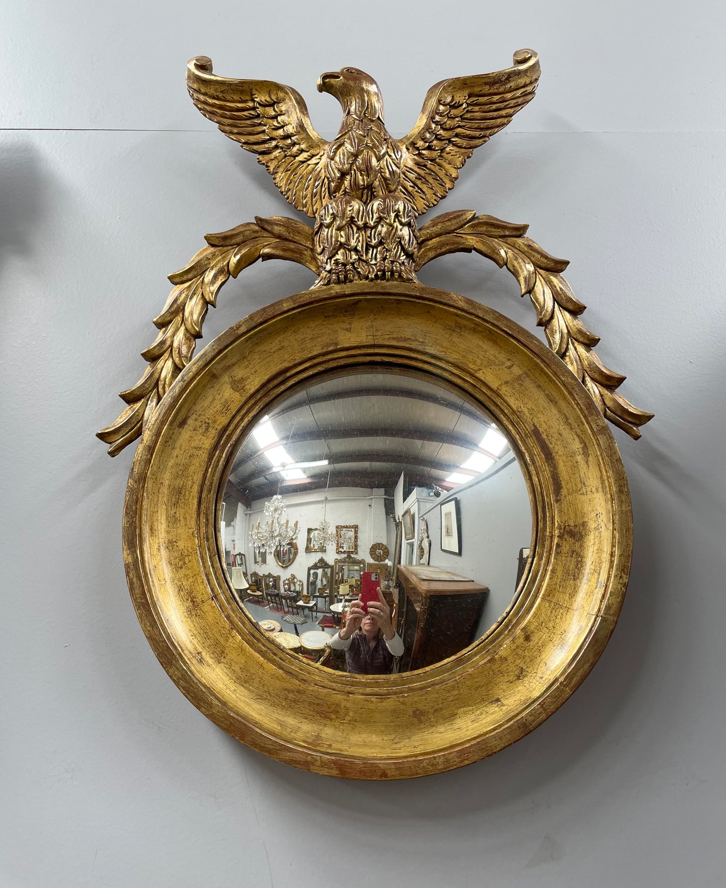 A stunning round carved wooden eagle convex hanging mirror. The eagle theme adds a touch of elegance and sophistication to your décor. It is in good as found condition.