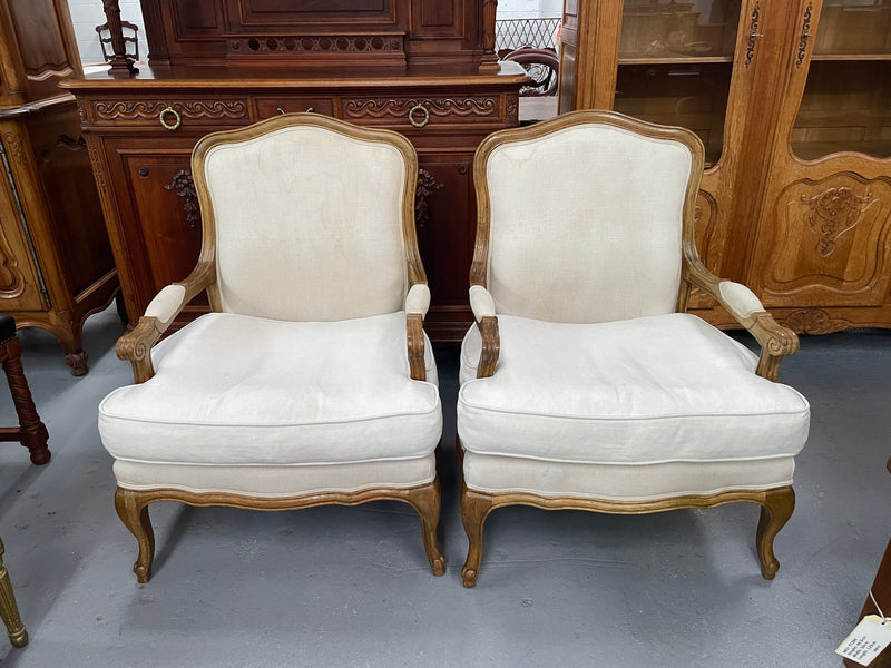 Pair of vintage Louis 15th style oak framed bergeres chairs with good size seats. making them very comfortable to sit in. The upholstery is in used condition with stains as shown in photos. Overall the timber frames are strong &amp; solid. They have been sourced directly from France. 