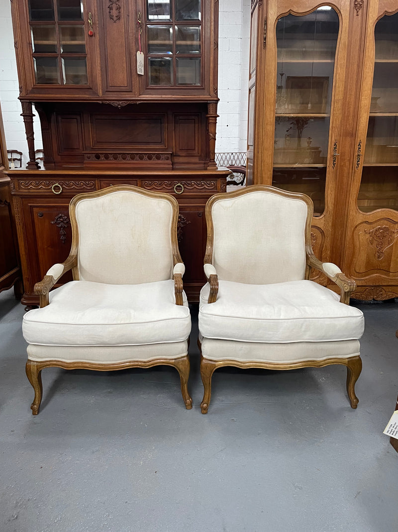 Pair of vintage Louis 15th style oak framed bergeres chairs with good size seats. making them very comfortable to sit in. The upholstery is in used condition with stains as shown in photos. Overall the timber frames are strong &amp; solid. They have been sourced directly from France. 