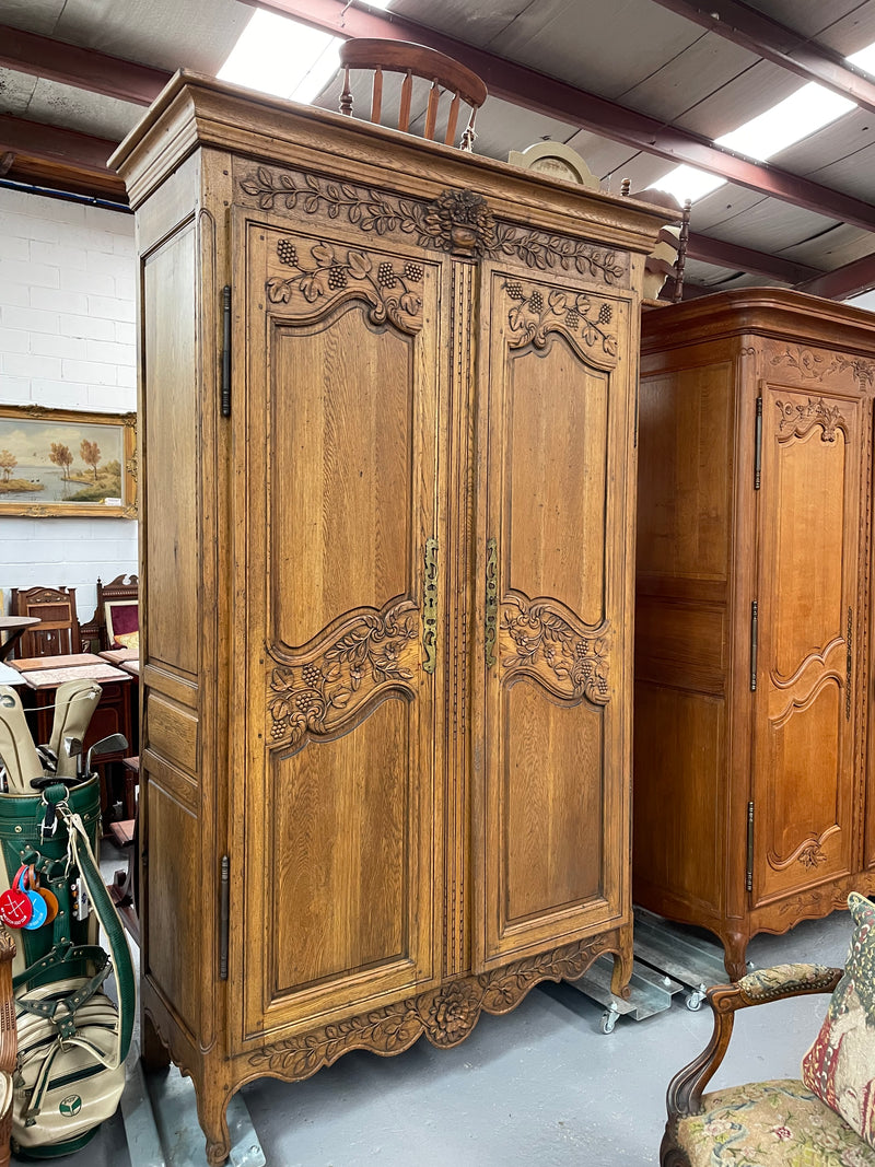Attractive French Oak two door decoratively carved armoire with hanging space and adjustable/removable shelves. Imported directly from France and is in good original detailed condition. 