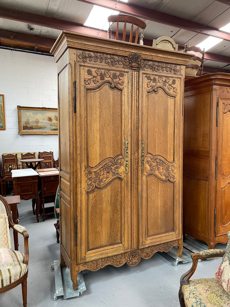 Attractive French Oak two door decoratively carved armoire with hanging space and adjustable/removable shelves. Imported directly from France and is in good original detailed condition. 