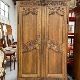 Attractive French Oak two door decoratively carved armoire with hanging space and adjustable/removable shelves. Imported directly from France and is in good original detailed condition. 