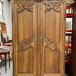 Attractive French Oak two door decoratively carved armoire with hanging space and adjustable/removable shelves. Imported directly from France and is in good original detailed condition. 