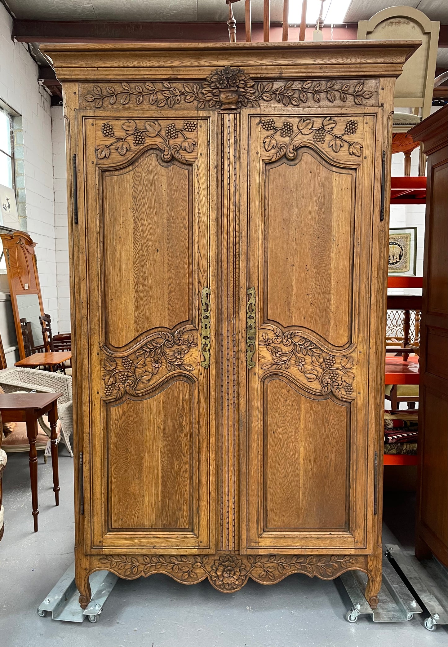 Attractive French Oak two door decoratively carved armoire with hanging space and adjustable/removable shelves. Imported directly from France and is in good original detailed condition. 