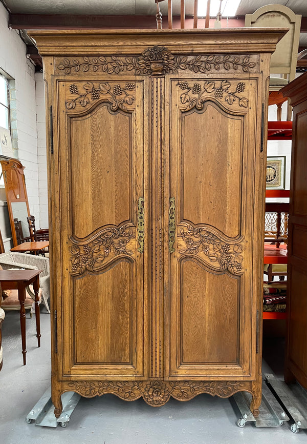 Attractive French Oak two door decoratively carved armoire with hanging space and adjustable/removable shelves. Imported directly from France and is in good original detailed condition. 