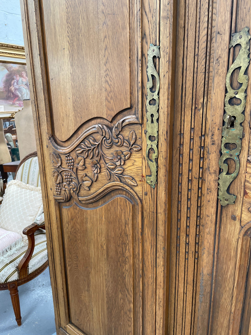 Attractive French Oak two door decoratively carved armoire with hanging space and adjustable/removable shelves. Imported directly from France and is in good original detailed condition. 