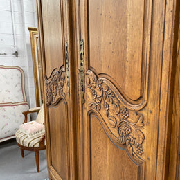 Attractive French Oak two door decoratively carved armoire with hanging space and adjustable/removable shelves. Imported directly from France and is in good original detailed condition. 