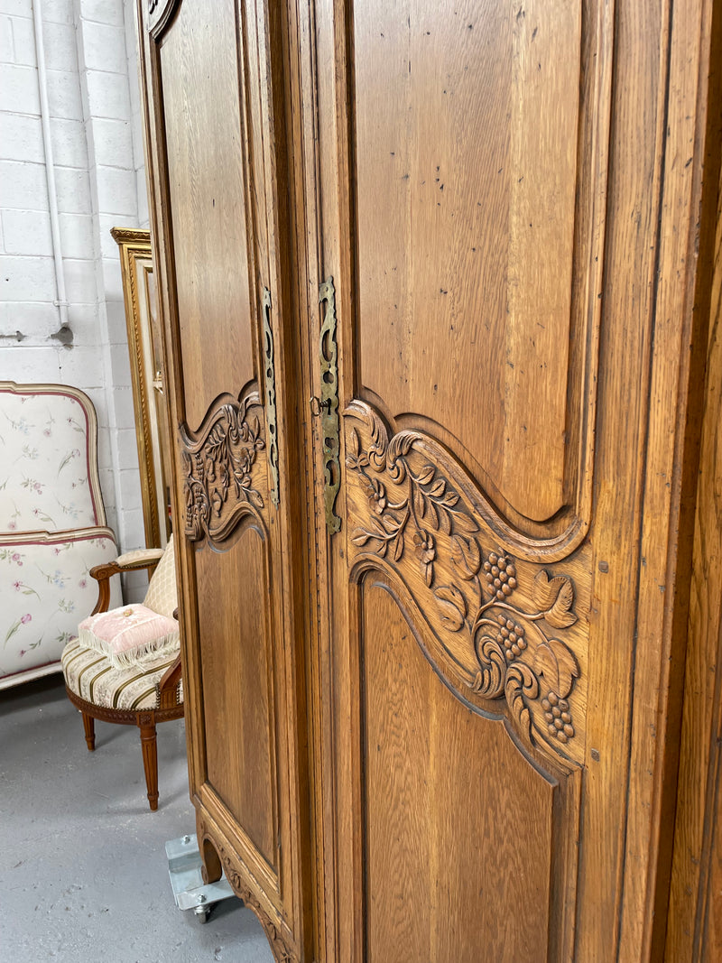 Attractive French Oak two door decoratively carved armoire with hanging space and adjustable/removable shelves. Imported directly from France and is in good original detailed condition. 
