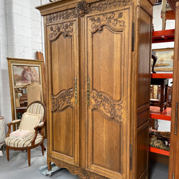 Attractive French Oak two door decoratively carved armoire with hanging space and adjustable/removable shelves. Imported directly from France and is in good original detailed condition. 