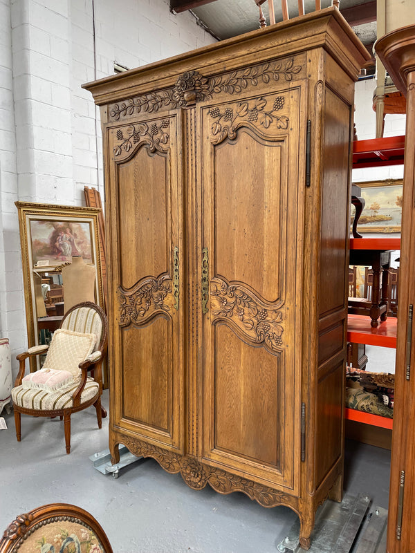 Attractive French Oak two door decoratively carved armoire with hanging space and adjustable/removable shelves. Imported directly from France and is in good original detailed condition. 