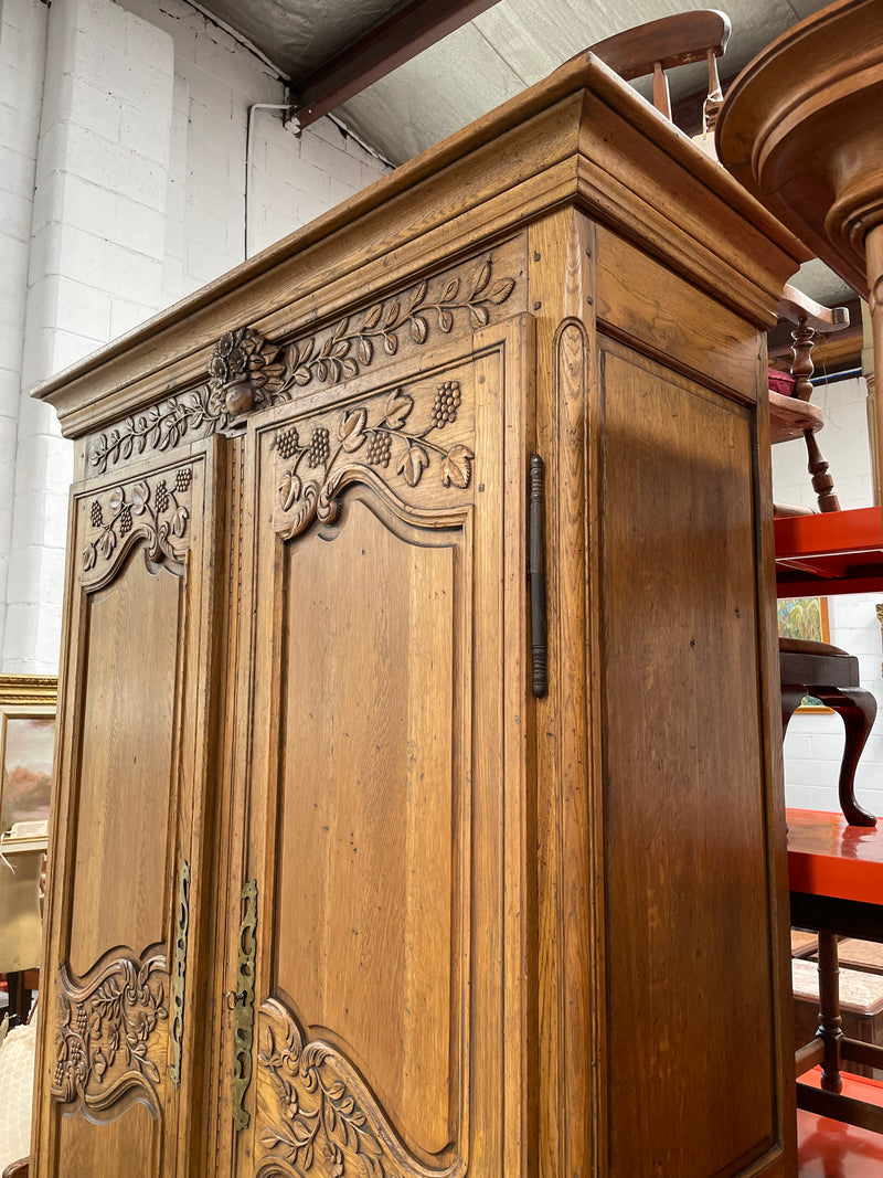Attractive French Oak two door decoratively carved armoire with hanging space and adjustable/removable shelves. Imported directly from France and is in good original detailed condition. 