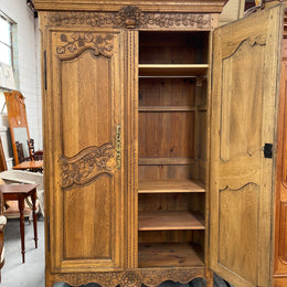 Attractive French Oak two door decoratively carved armoire with hanging space and adjustable/removable shelves. Imported directly from France and is in good original detailed condition. 