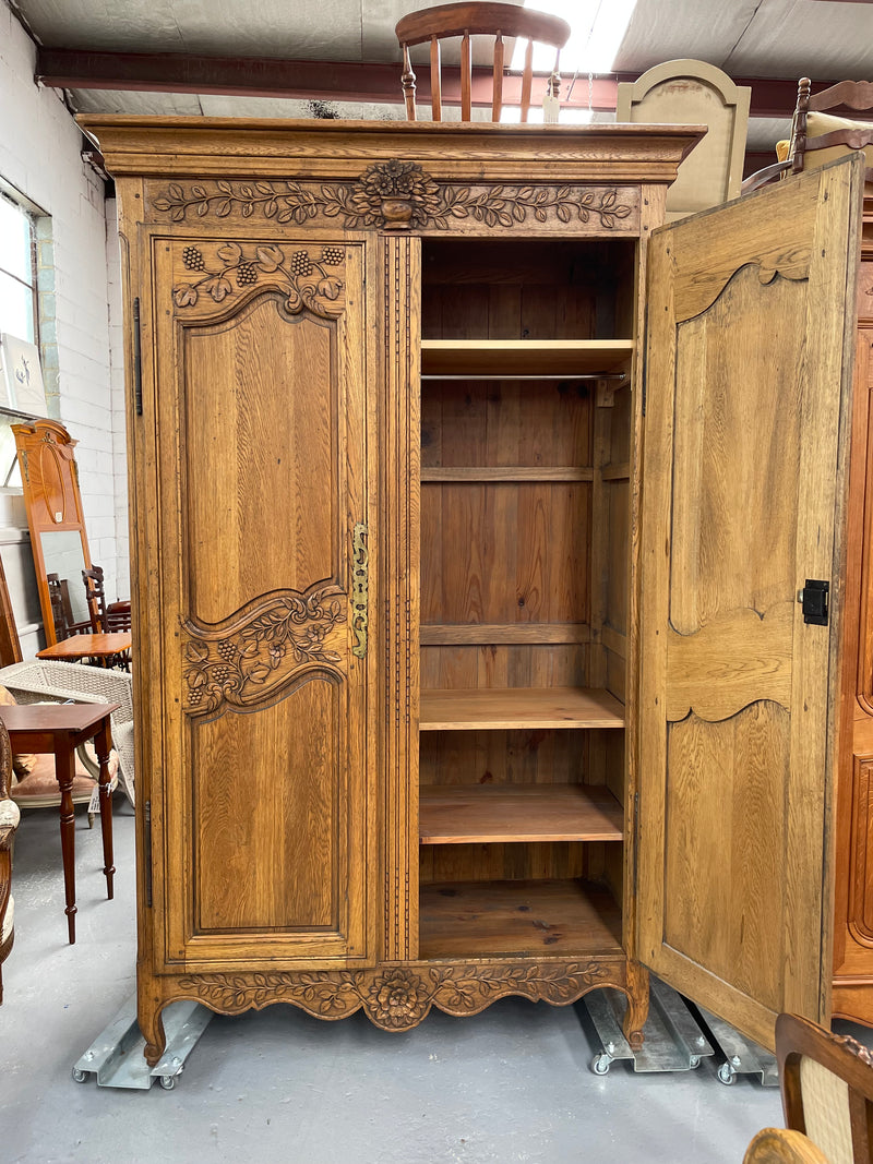 Attractive French Oak two door decoratively carved armoire with hanging space and adjustable/removable shelves. Imported directly from France and is in good original detailed condition. 