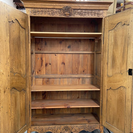 Attractive French Oak two door decoratively carved armoire with hanging space and adjustable/removable shelves. Imported directly from France and is in good original detailed condition. 