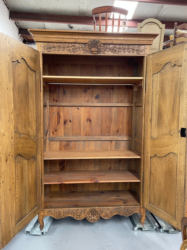 Attractive French Oak two door decoratively carved armoire with hanging space and adjustable/removable shelves. Imported directly from France and is in good original detailed condition. 