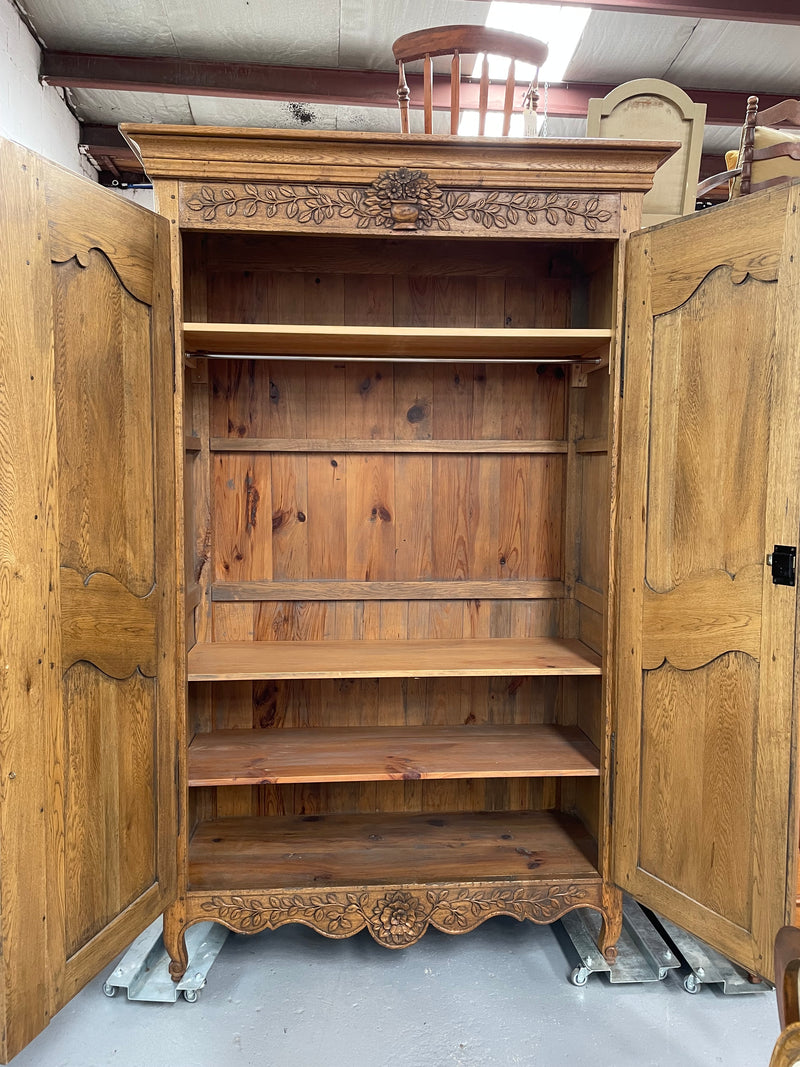 Attractive French Oak two door decoratively carved armoire with hanging space and adjustable/removable shelves. Imported directly from France and is in good original detailed condition. 