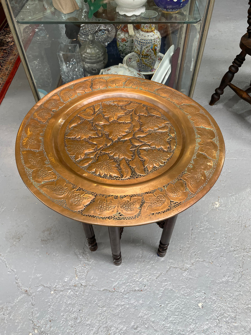 Middle eastern carved folding bases coffee table. It has a copper top intricately pierced and patterned. It is in good original condition. Please see photos as they form part of the description and condition.