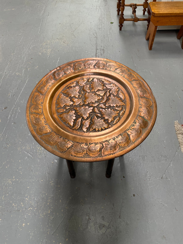 Middle eastern carved folding bases coffee table. It has a copper top intricately pierced and patterned. It is in good original condition. Please see photos as they form part of the description and condition.